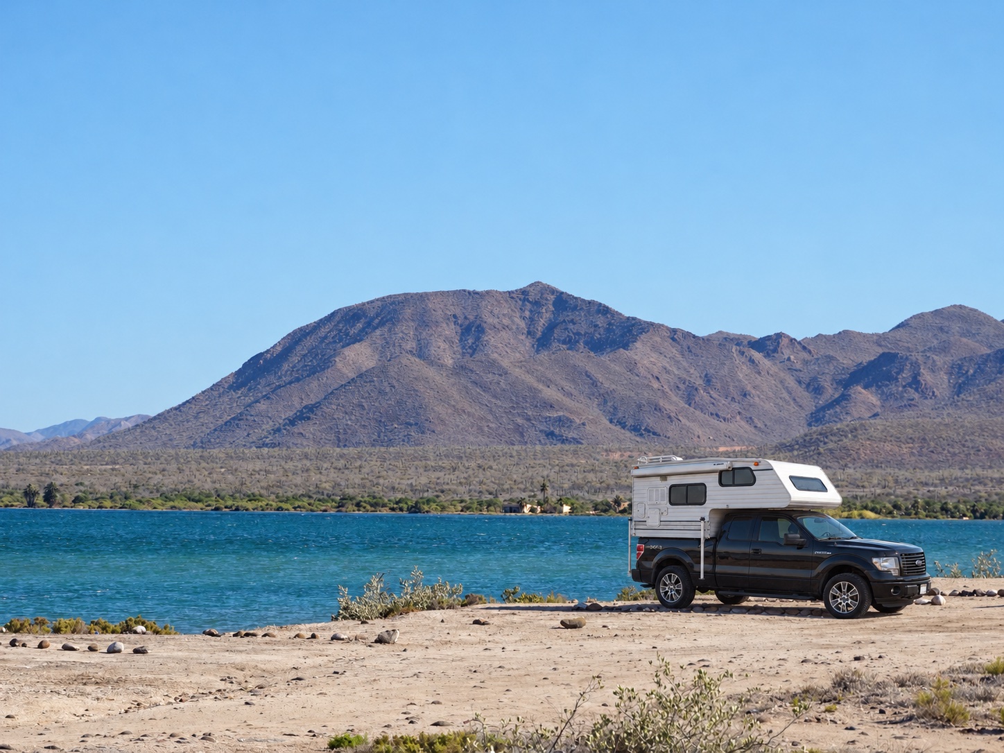 Camper illustration beside a blue bay and mountains